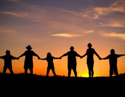 People hand in hand with sunset behind them
