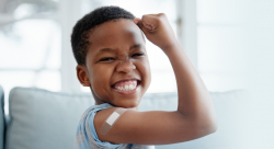 Boy with bandage on arm after vaccination flexing bicep