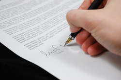Hand with pen signing a form