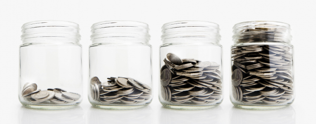 Four clear jars in a row, each with more coins in them.