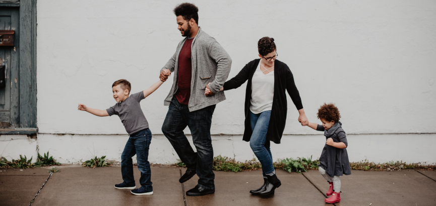 Family with two children holding hands. 