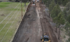 Aerial view of road work on a rural road lined with trees and power lines